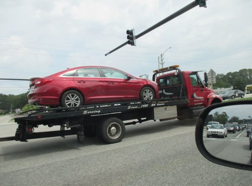 Flatbed Tow truck with a car on it in jacksonville florida